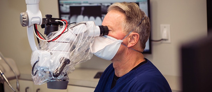 doctor looking through microscope in dental office